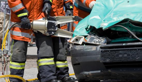 Pelastaja katkaisee hydraulileikkurilla henkilöauton palkkia. 